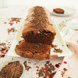 Schokokuchen in Kastenform mit flüssigem Schokoüberzug und Schokostreuseln.