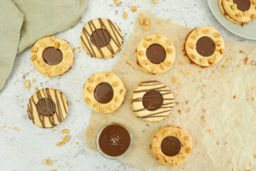 Neun runde Doppelkekse. Loch im oberen Keks - mit Karamell gefüllt. Verziert mit Erdnüssen und Schokolade.